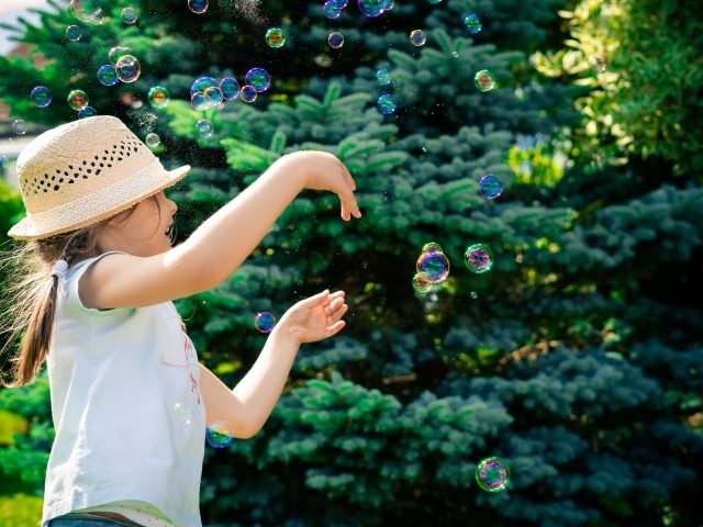 Маленькая девочка с мыльными пузырями у елки