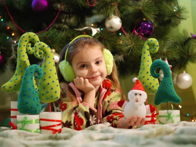 Маленькая девочка с игрушками под елкой 