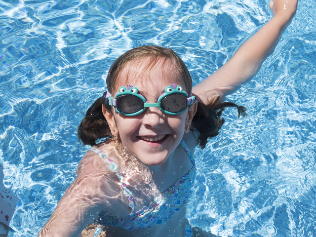 Маленькая улыбающаяся девочка в очках в бассейне 
