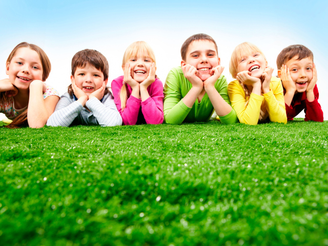 Улыбающиеся дети лежат на зеленой траве