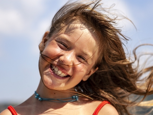 Ветер развивает волосы улыбающейся девочки