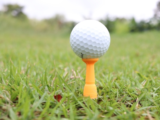 Мячик для гольфа на поле с зеленой травой 