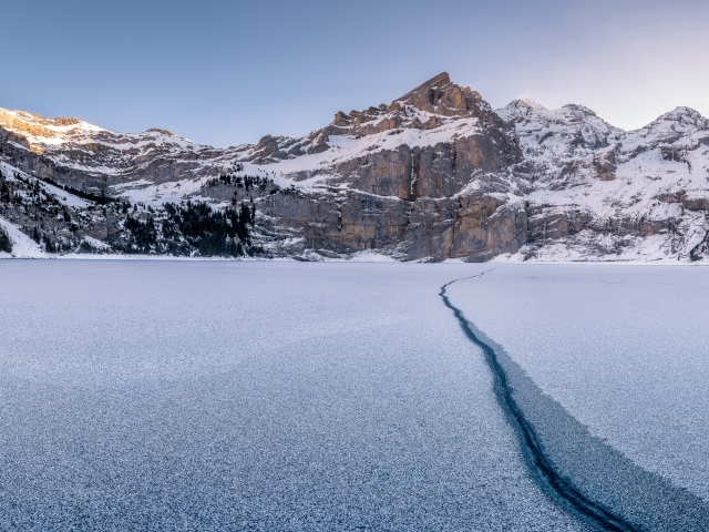 Трещина в озере на фоне заснеженных гор зимой
