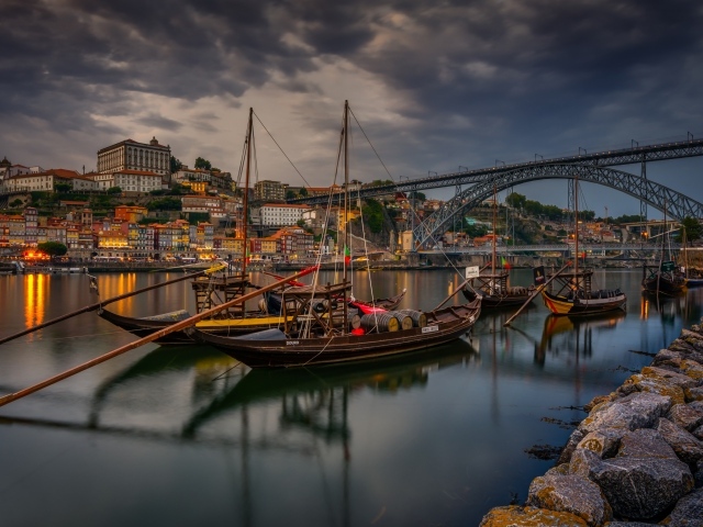 Лодки в порту на фоне моста и города на закате 