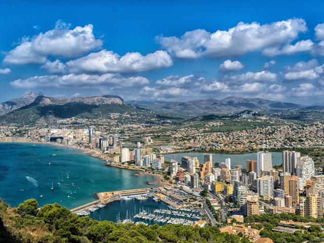 Вид на на город у гор под голубым небом с белыми облаками, Испания 