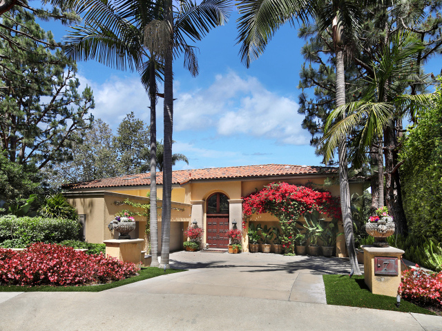 Дом на улице с цветущими кустами и пальмами