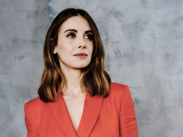 Актриса Элисон Бри в красном пиджаке на сером фоне
