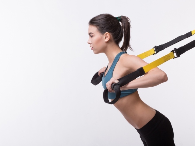 Спортивная девушка занимается в спортзале на белом фоне 