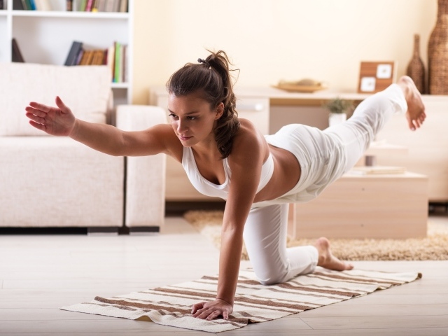 Красивая девушка в белом костюме занимается фитнесом дома