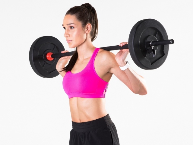 Красивая спортивная девушка со штангой на белом фоне