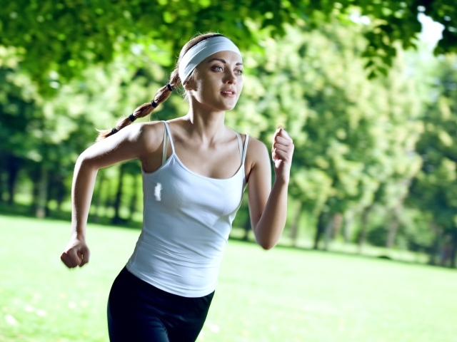 Девушка спортсменка в белой майке занимается бегом