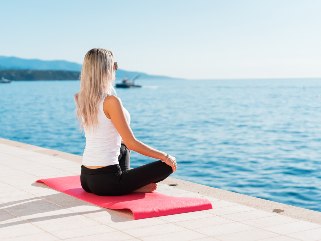 Девушка медитирует на берегу моря 