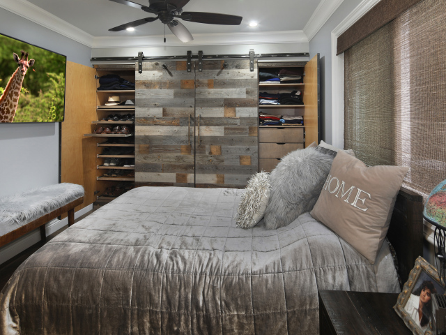 Большая серая кровать в спальне с деревянным интерьером