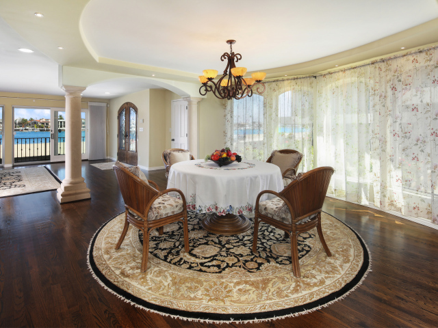 Большая гостиная комната с большими окнами и столом 