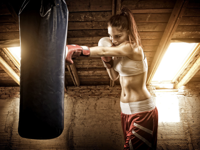 Спортивная девушка бьет боксерскую грушу 