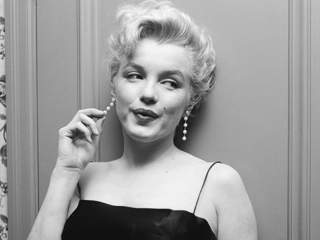 Легендарная Мэрилин Монро стоит у стены, черно -белое фото