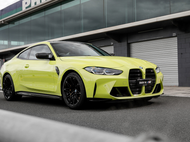 Желтый автомобиль BMW M4 Competition 2021 года у здания