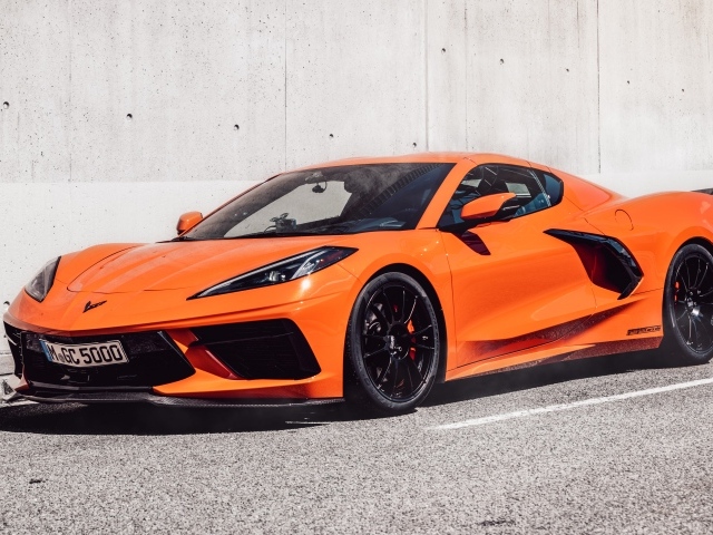 Оранжевый Chevrolet Corvette 2021 года на фоне серой стены