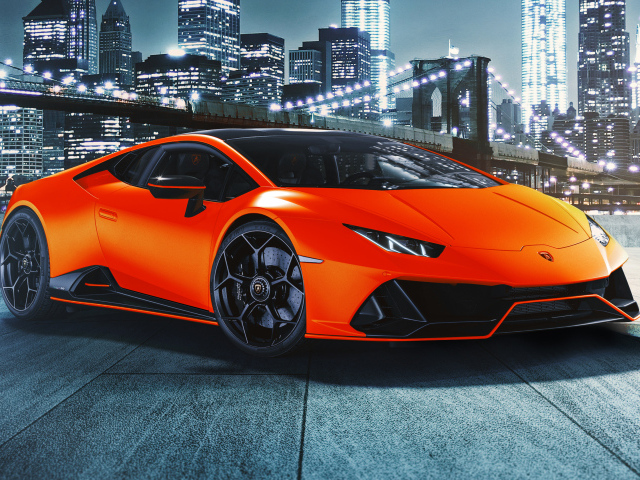 Оранжевый автомобиль Lamborghini Huracán EVO 2021 года на фоне небоскребов