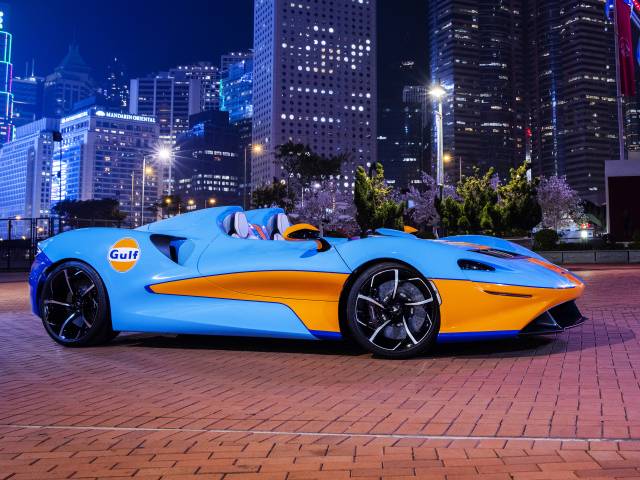 Автомобиль McLaren Elva Gulf Theme, 2021 года на фоне города