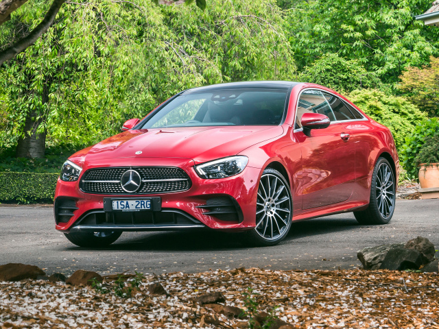 Красный автомобиль Mercedes-Benz E 300 AMG, 2020 года у дома осенью