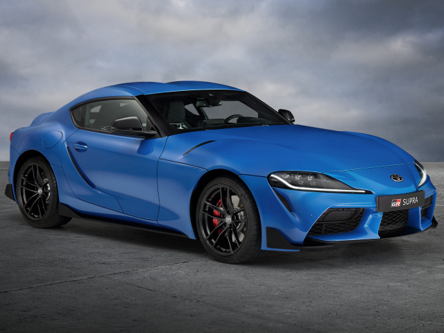 Синий автомобиль Toyota GR Supra, 2021 года на сером фоне