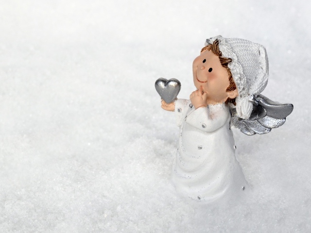 Статуэтка ангела стоит на снегу 