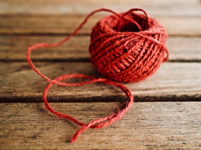 Клубок красной пряжи на деревянном столе 