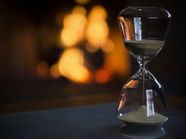 Стеклянные песочные часы на столе 