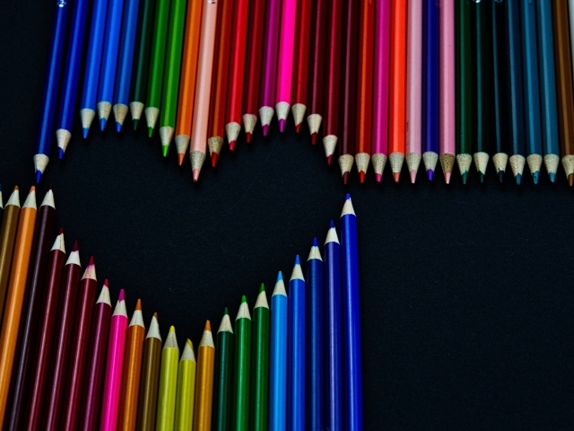 Сердце из разноцветных карандашей на черном фоне