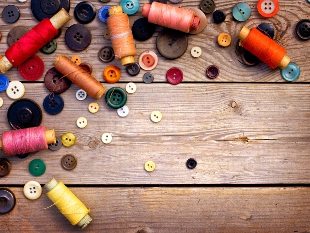 Разноцветные пуговицы и нитки лежат на столе