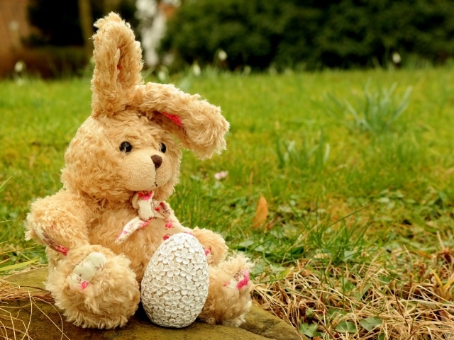 Игрушка заяц на камне в траве