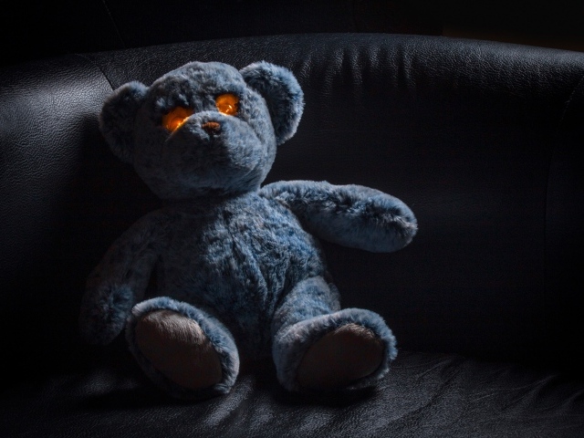 Игрушка со светящимися глазами на черном диване