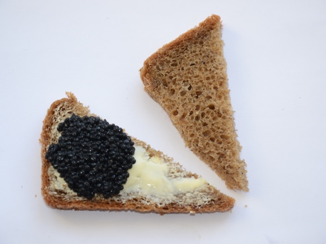 Бутерброды из черного хлеба с черной икрой на сером фоне