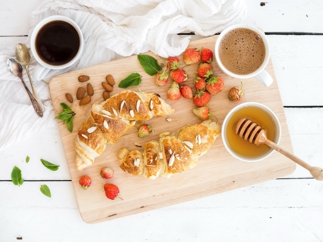 Круассаны на столе с орехами, клубникой и кофе