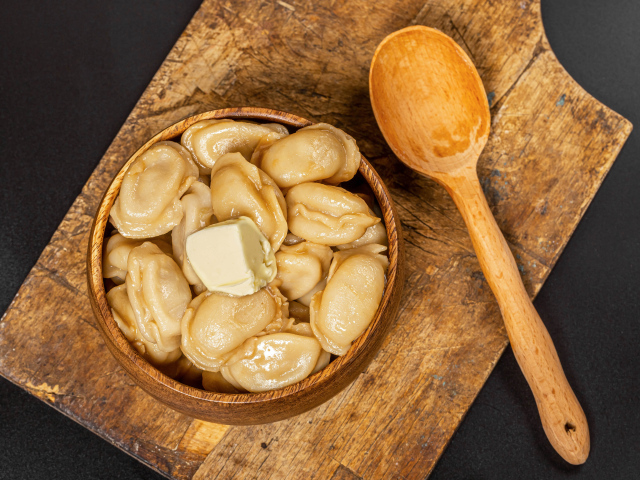 Пельмени в деревянной миске с маслом