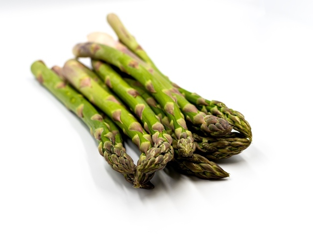 Свежая зеленая спаржа на белом столе