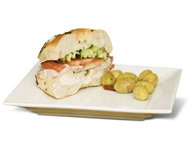 Половина гамбургера на тарелке с оливками