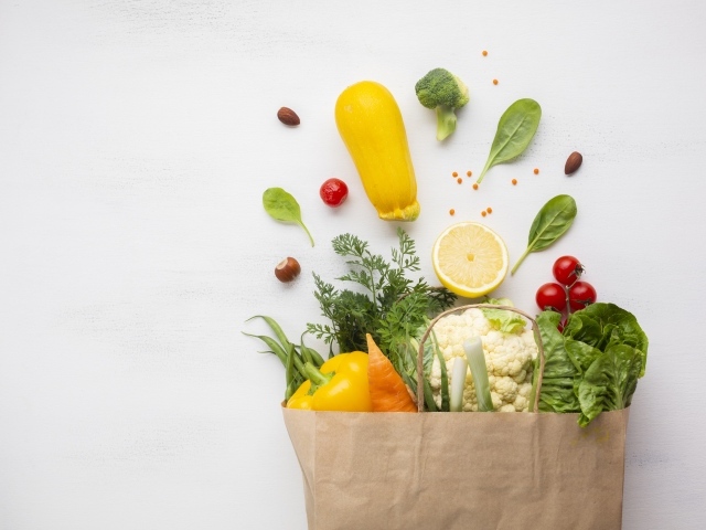 Пакет со свежими овощами и зеленью на сером фоне 