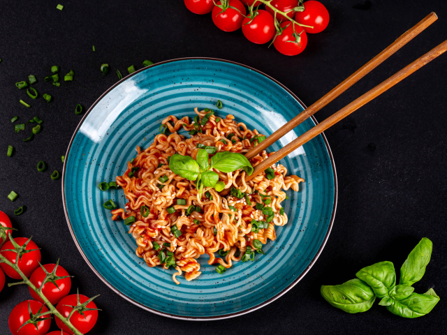 Макароны в соусе на столе с помидорами