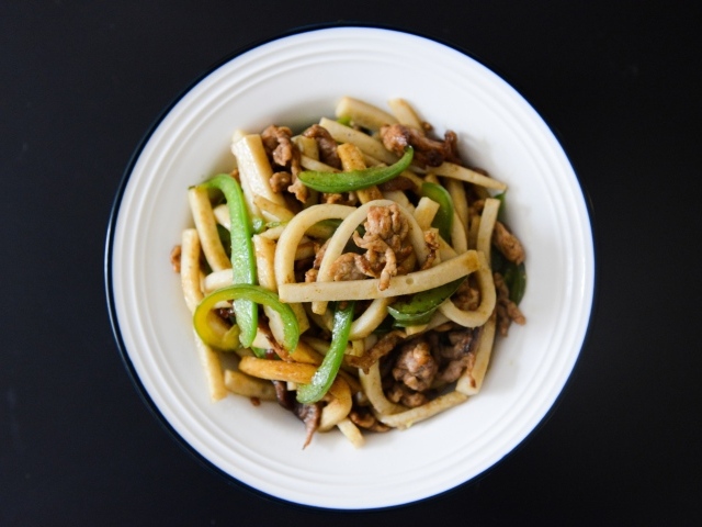 Салат с мясом в белой тарелке на черном фоне