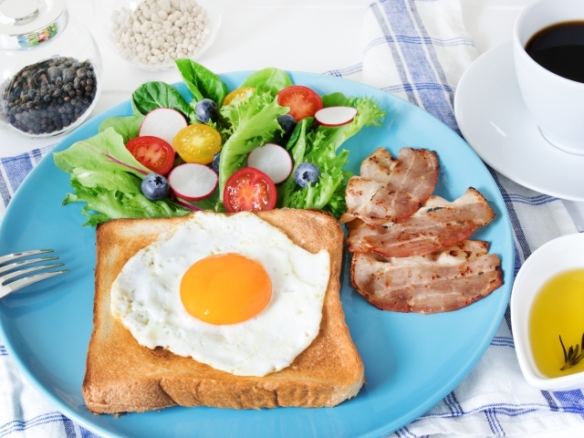 Яичница с хлебом на тарелке с салатом и беконом 