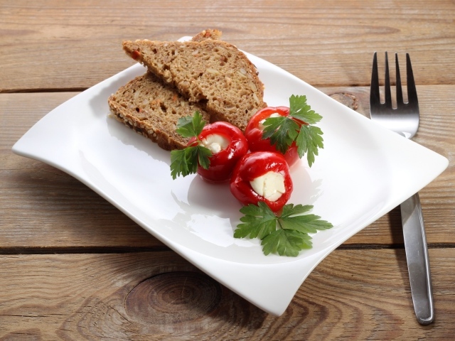 Фаршированный перец на большой белой тарелке с хлебом