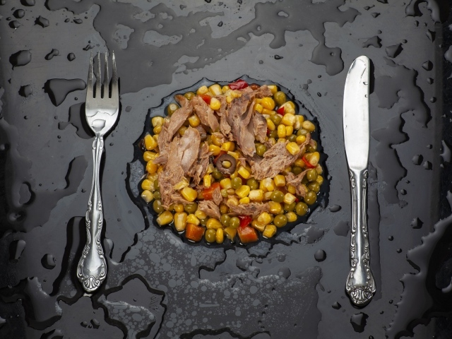 Овощи с мясом и столовыми приборами на черной поверхности