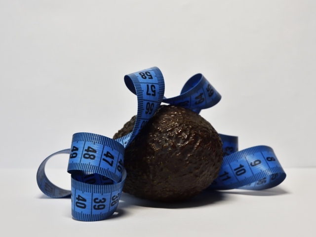 Авокадо с сантиметром на сером фоне