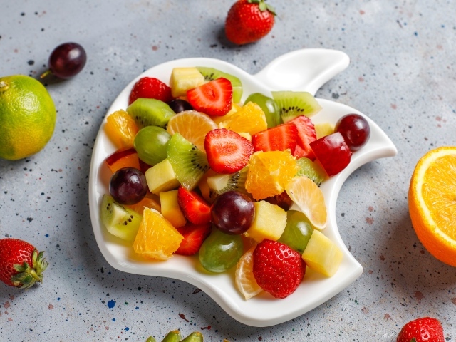 Фруктовый салат на белой тарелке на столе 