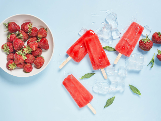 Мороженое со льдом и ягодами клубники на голубом фоне 