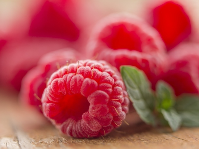 Крупная красная малина на столе с листьями мяты