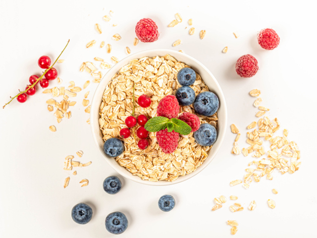 Овсяные хлопья с ягодами черники и малины на белом фоне 