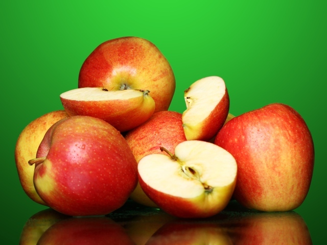 Спелые вкусные красные яблоки на зеленом фоне